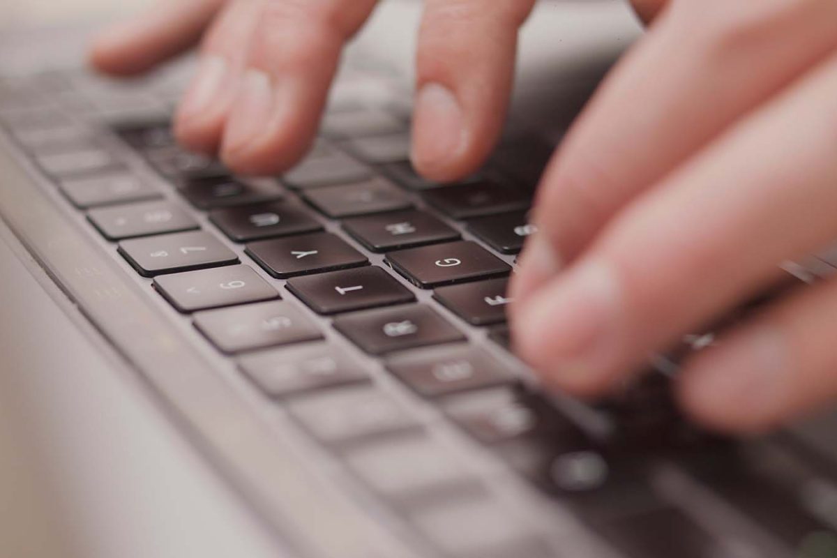 Close up macro of hands typing on laptop keyboard mac computer
